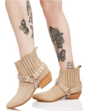 Quinceanera image of a woman wearing high-heeled shoes and tan boots with tattoos on her legs