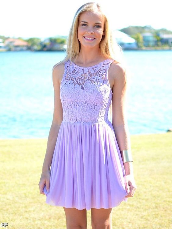 A woman wearing a lavender Quinceanera dress standing in front of a body of water.