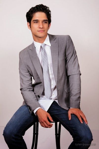 Tyler Posey, a man in a suit and tie, sitting on a chair during a Quinceanera photoshoot