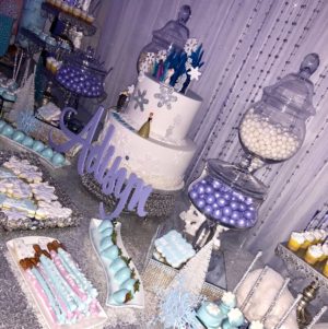 A Quinceanera-themed image featuring a lavender cupcake and a table filled with various desserts.