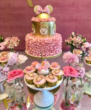 A Quinceanera-themed cake decoration with a table topped with cupcakes and a cake