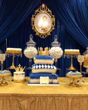 A Quinceanera candy table decorated in blue and gold. The table is adorned with a variety of blue and white desserts.
