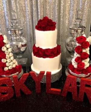 Quinceanera cake, a table topped with a white cake covered in red roses