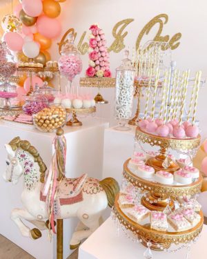A pink and gold Quinceanera cake decorated with sugar cake and a carousel