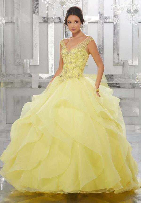 A woman in a yellow ball gown wearing Quinceañera dresses with yellow quinceanera makeup