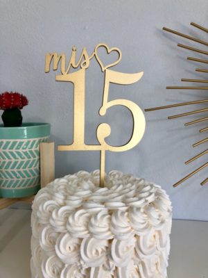 A Quinceanera cake with a cake topper and a name decoration