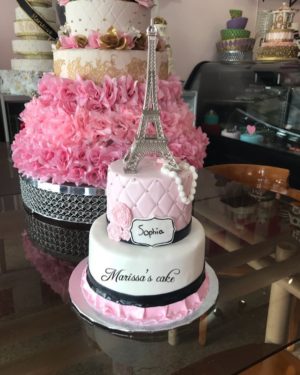 A three-tiered Quinceanera cake with a buttercream design featuring the Eiffel Tower on top