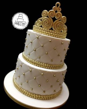 A three tiered Quinceanera cake decorated with a gold crown on top