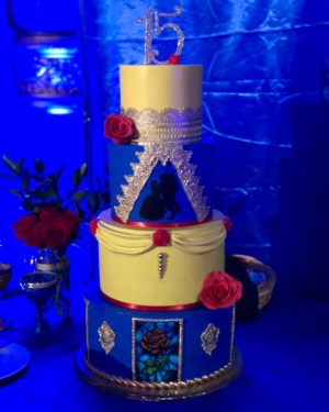 A Quinceanera cake, a three tiered cake with red roses on a table