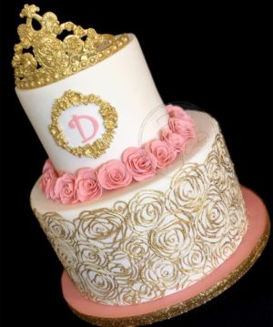 Quinceanera cake, a white and pink cake with a gold crown on top, decorated with Quinceanera theme