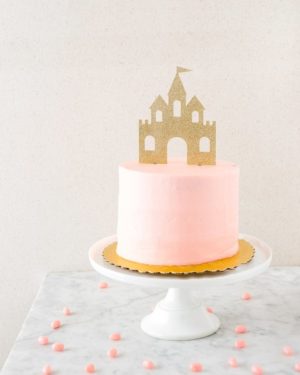 A Quinceanera cake with a pink sugar castle on top.