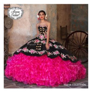 A woman in a pink and black charro Quinceañera dress posing for a picture