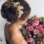 A woman in a black dress holding a bouquet of cut flowers, showcasing a Quinceanera hairstyle.