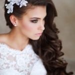 A woman with long hair wearing a side brooch hairstyle and a white dress for a Quinceanera celebration