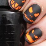 A person holding a black and orange manicure with nail designs inspired by Quinceanera decorations and the colors of a jack o' lantern.