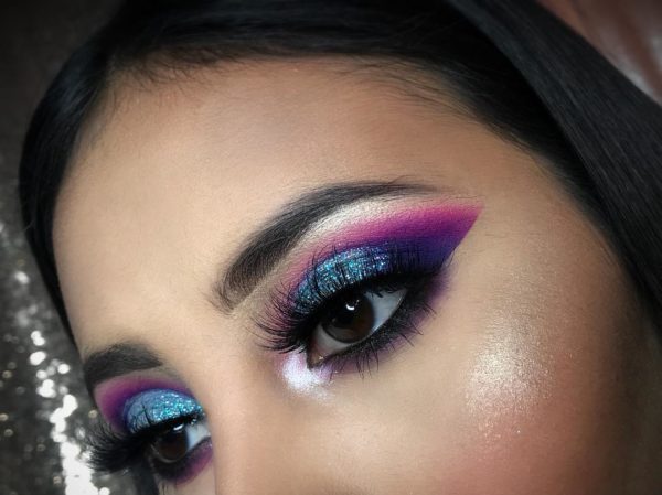 A close up of a woman's face with purple and blue eyeshadow, perfect for a Quinceanera look.
