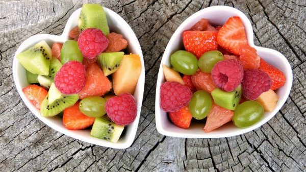 Quinceanera image of two heart shaped bowls filled with fruit on top of a wooden table, representing nutrient-rich and healthy food for older adults