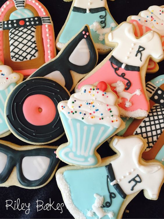 A bunch of decorated cookies on a table, with a 1950s Quinceanera theme