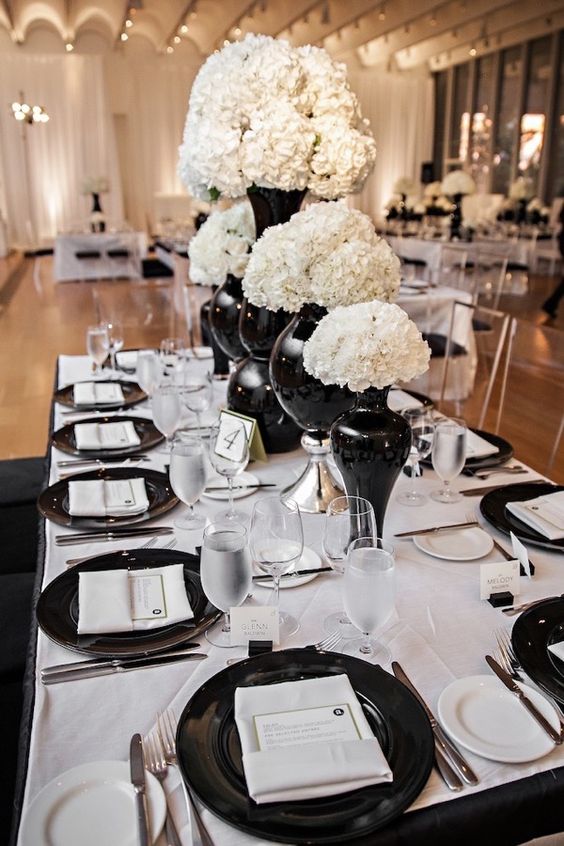 Quinceanera decor: black and white table set with black plates and white flowers