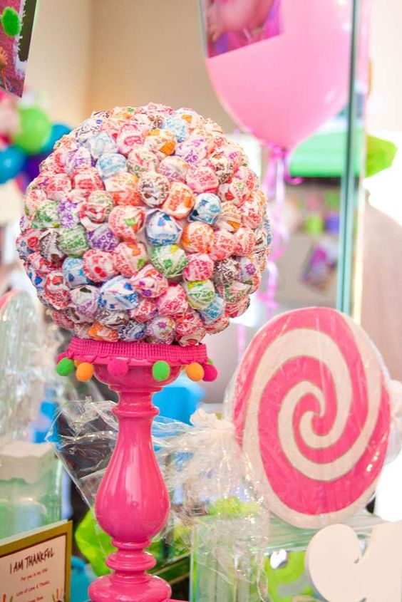 A Quinceanera party with a table filled with a variety of candy and lollipops