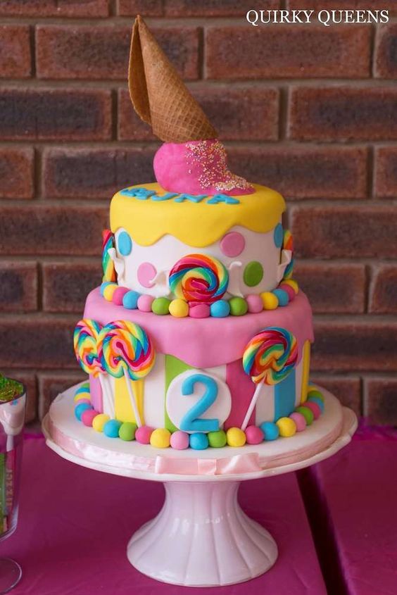 A Quinceanera birthday cake with a cone on top, decorated in a candyland theme
