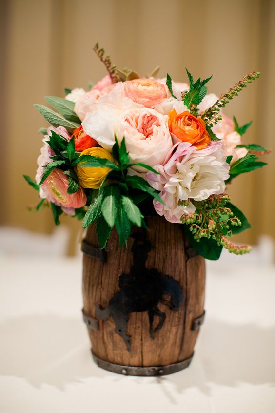 A Quinceanera table centerpiece featuring a vase filled with flowers, sitting on top of a table.