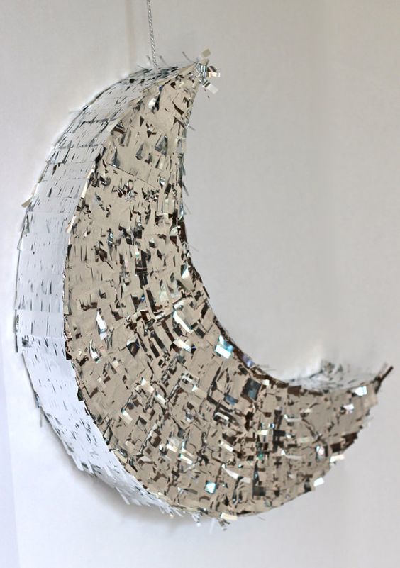A Quinceanera themed image of the kelpies Piñata, a mirror shaped like a half moon hanging on a wall.