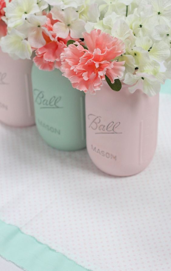 Three mason jars with Quinceanera floral design, filled with flowers, on a table