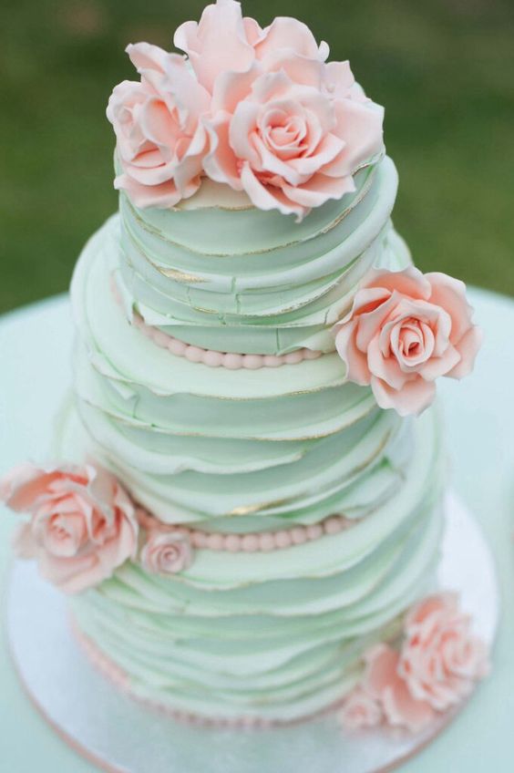 A Quinceanera themed cake Cupcake featuring a three-tiered design with light pink and light green colors. The top tier is adorned with pink flowers.