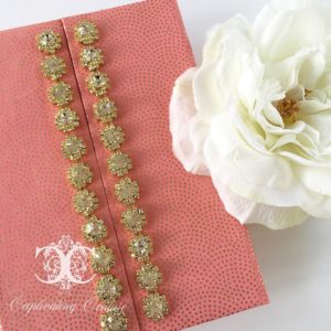 A Quinceanera themed image featuring artificial plants, a white flower, and a pink book with gold trim.