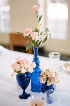 Quinceanera centrepiece floral design, three blue vases filled with flowers on a table