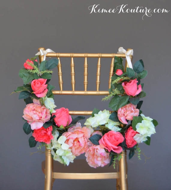 A Quinceanera flower bouquet table with a chair adorned with a wreath of flowers
