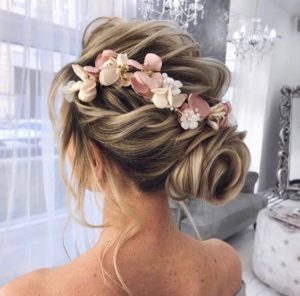 A Quinceanera woman with a chignon hairstyle and a flower in her hair