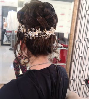 A woman getting her hair done in a salon with a chignon hairstyle for Quinceanera