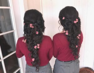 Two women with long black hair standing next to each other, showcasing a Quinceanera hairstyle.