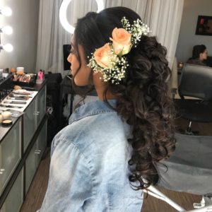 Quinceanera hairstyles ponytail. A woman with long hair wearing a flower in her hair.