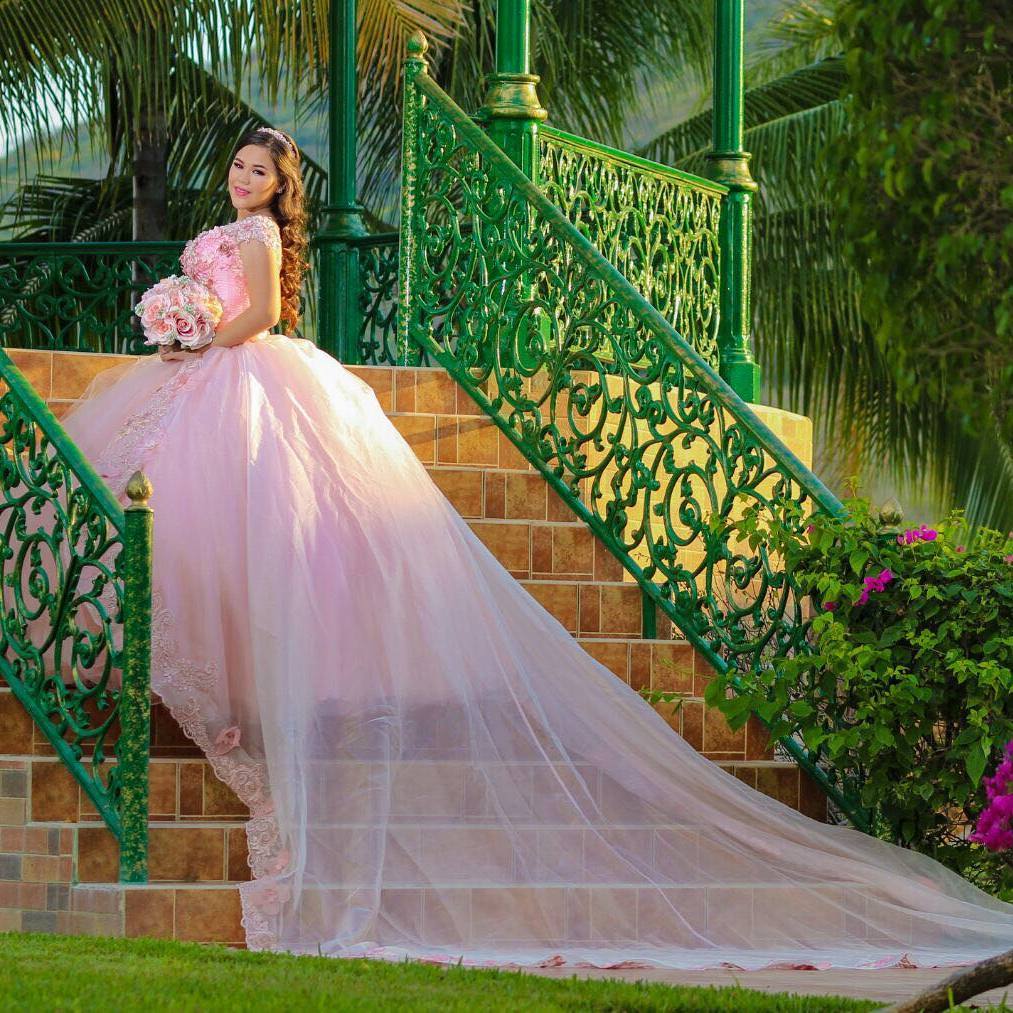 A woman wearing a Quinceanera gown, sitting on a set of stairs