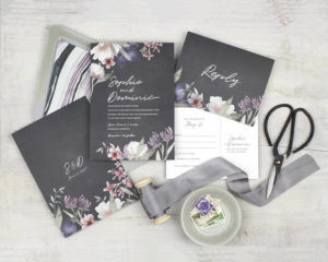 A Quinceanera-themed image with a lilac grey color scheme. The image features a table adorned with a variety of stationery items and a pair of scissors.