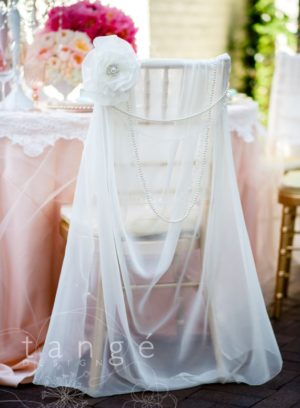 A stunning quinceanera gown displayed on a white chair adorned with a beautiful white flower.