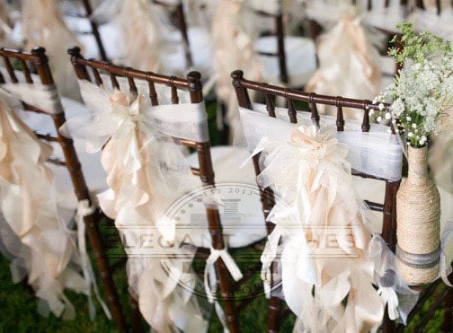 A row of chairs covered with burlock and flowers at a Quinceanera aisle