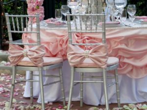 A Quinceanera table with a bunch of chairs covered in pink fabric