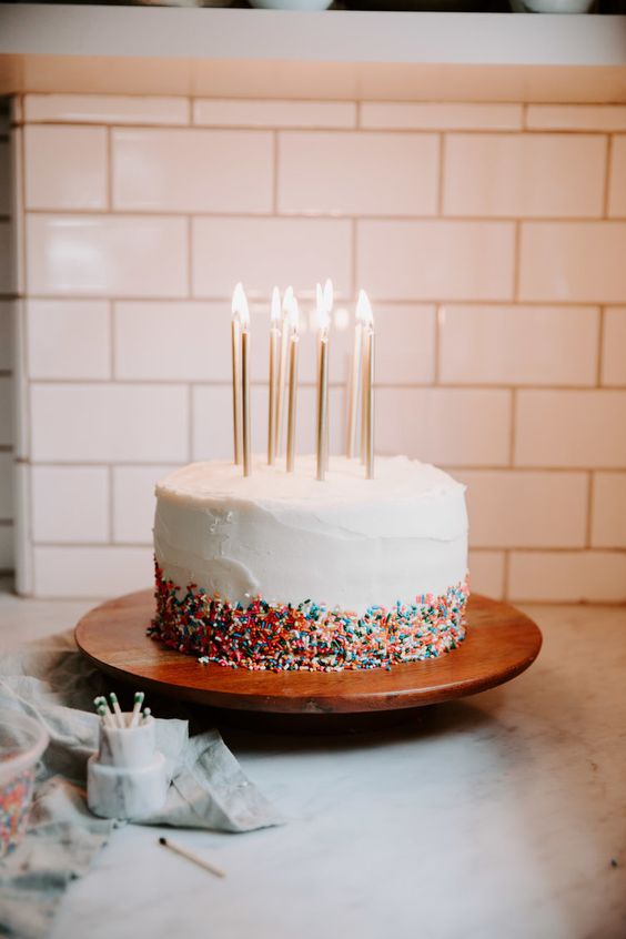 A Quinceanera cake with candles and a cupcake on top
