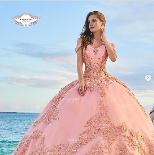A woman in a pink Quinceañera gown standing on a beach