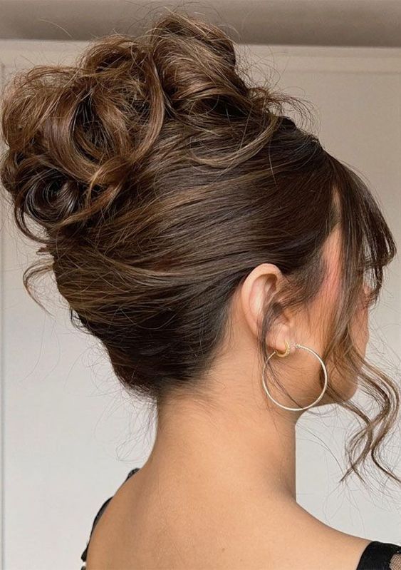 A woman with her hair in a messy bun, showcasing a prom hair bun hairstyle for a Quinceanera event