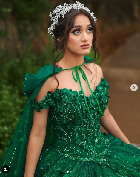 A woman in a green dress posing for a picture, wearing a gown Quinceañera dress