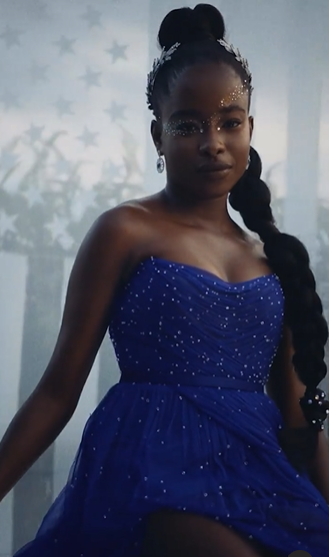 A beautiful woman in a blue dress posing for a picture at a Quinceanera event with a Met Gala theme.