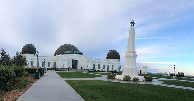 A Quinceanera celebration at Griffith Observatory, a large white building with two domes on top of it against a blue sky.