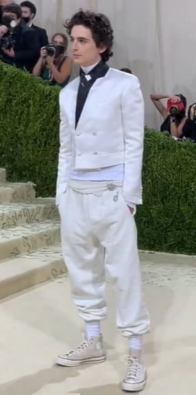 A fashion model Timothée Chalamet, a man in a white suit and black tie, at a Quinceanera event.