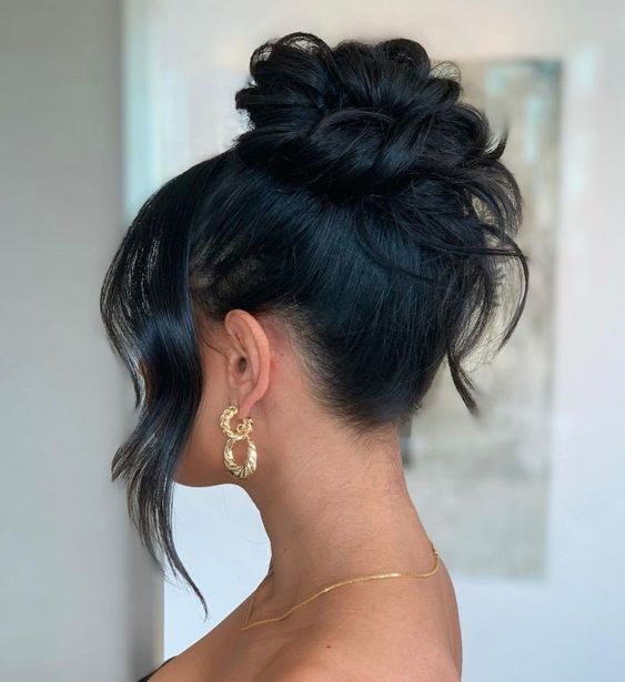 A woman with long black hair wearing a gold hoop earrings at a Quinceanera celebration.