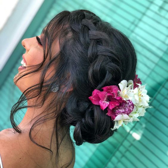 A woman with long hair and a flower in her hair, wearing a Quinceanera dress.